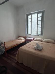 two beds in a room with a window at Hostel Bahia POA Próx Shopping Total, Rodoviária e Hospital Presidente Vargas in Porto Alegre