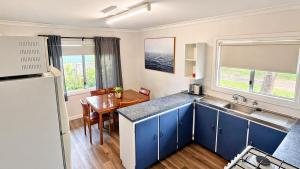 a kitchen with blue cabinets and a sink and a table at Family Beachside Shack in Geographe