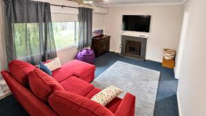 a living room with a red couch and a television at Family Beachside Shack in Geographe