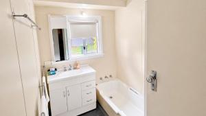 a white bathroom with a sink and a bath tub at Family Beachside Shack in Geographe +28 photos