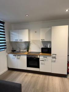 a kitchen with white cabinets and a black microwave at Chic Design and Modern Comfort - 1BR with Sofa Bed in Liège