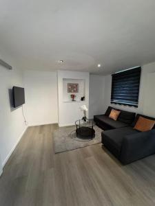 a living room with a black couch and a television at Chic Design and Modern Comfort - 1BR with Sofa Bed in Liège