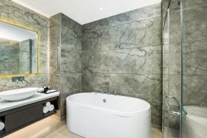 a bathroom with a white tub and a sink at DoubleTree by Hilton Hotel Goa - Arpora - Baga in Baga