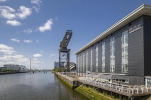 a building with a crane next to a river at Hilton Garden Inn Glasgow City Centre in Glasgow