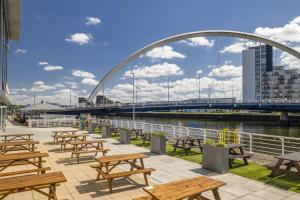 a group of picnic tables with a bridge in the background at Hilton Garden Inn Glasgow City Centre in Glasgow