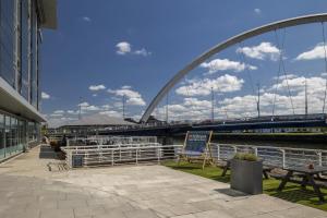 a bridge over a river with a bench and a sign at Hilton Garden Inn Glasgow City Centre in Glasgow