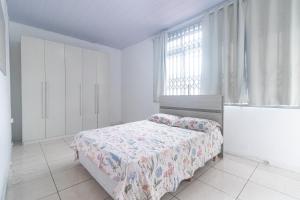 a white bedroom with a bed and a window at Guest House Central in Florianópolis