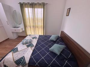 a bedroom with a bed with a blue comforter and a window at Podcast House in Chikmagalūr