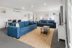 a living room with two blue couches and a table at Bay View - Lounge Lovers in Lorne