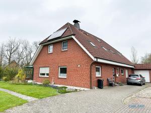 ein rotes Backsteinhaus mit einem in der Einfahrt geparkten Auto in der Unterkunft Medemblick in Ihlienworth