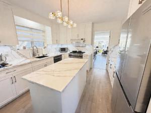 a large kitchen with white cabinets and a refrigerator at Vancouver Lucy House in Vancouver