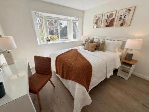 a white bedroom with a bed and a window at Vancouver Lucy House in Vancouver