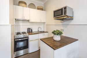 a kitchen with white cabinets and a stove and a microwave at Centennial Cottage 1 - 'Boorool' in Bowral