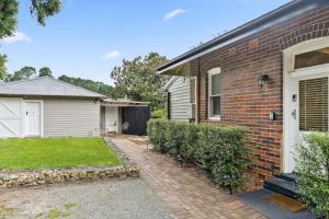 a brick house with a white door and a yard at Centennial Cottage 1 - 'Boorool' in Bowral