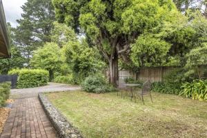 a garden with a table and chairs and a tree at Centennial Cottage 1 - 'Boorool' in Bowral