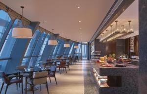 a restaurant with blue walls and tables and chairs at Hilton Haikou in Haikou