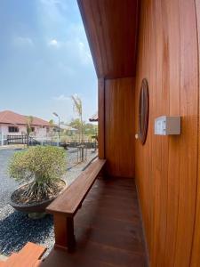 a wooden bench sitting on the side of a building at Gun Eng Resort กันต์เองรีสอร์ท in Ban Nong Nam Sang