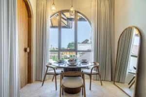 a dining room with a table and chairs and a window at Maison Boheme Modern Apartment & Villa with Pool in Sanur in Sanur