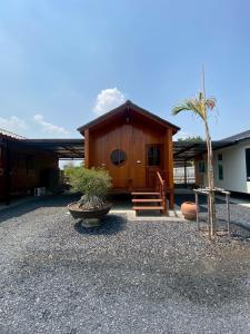 a small wooden cabin with a porch and a tree at Gun Eng Resort กันต์เองรีสอร์ท in Ban Nong Nam Sang