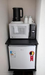 a microwave and a toaster oven on top of a refrigerator at Suíte Executiva - Climatizada in Erval dʼOeste