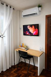 a room with a desk and a tv on the wall at Suíte Executiva - Climatizada in Erval dʼOeste