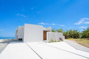 a white house with the ocean in the background at Tamagusuku Terrace in Nanjo