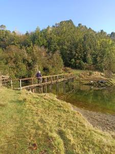 a man walking across a wooden bridge over a river at Luz de mareas in Ancud