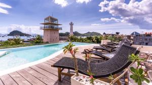 a pool with lounge chairs and a lighthouse on a building at Oh!Julia Hotel Komodo in Labuan Bajo