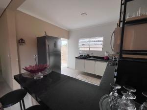 a kitchen with a black counter top and a refrigerator at A Casa da Sogra in Bertioga