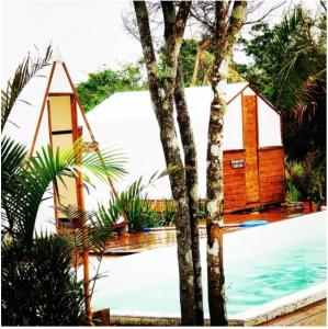 a house next to a swimming pool with a tree at Chalés & glamping primitivo Búzios in Búzios