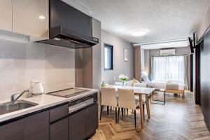 a kitchen with a sink and a table with chairs at Hopetree NambaImamiya in Osaka