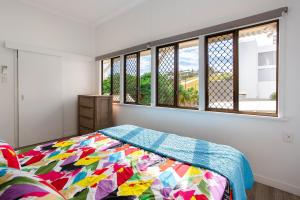 a bedroom with a bed with a colorful blanket at Sunrise on the Esplanade in Yeppoon