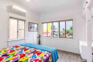 a bedroom with a colorful bed and windows at Sunrise on the Esplanade in Yeppoon