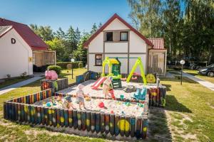 a playground with three children playing in a sandbox at Comfortable holiday home, summer pool in Łeba