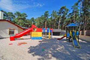 a playground with a red slide and a play structure at Comfortable holiday home, summer pool in Łeba