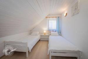 two beds in a white room with a window at Comfortable holiday home, summer pool in Łeba +27 photos