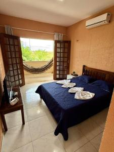 a bedroom with a bed with blue sheets and a window at Pousada VillageMar in Cascavel