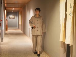 a man walking down a hallway wearing a trench coat at Takarazuka Washington Hotel in Takarazuka +82 photos