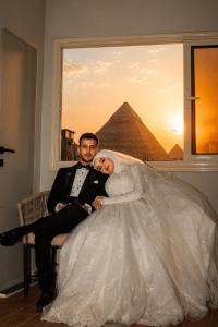 a bride and groom posing for a picture in front of the pyramids at Calm Pyramids View Villa in Cairo