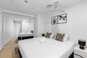 a white bedroom with two beds and a mirror at CBD RiverView 2Bed Apt Kingbed at Tallest building in Brisbane +34 photos