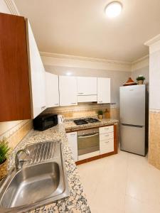 a kitchen with white cabinets and a stainless steel sink at Résidence El Harti in Marrakesh +5 photos