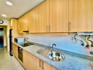 a kitchen with a sink and wooden cabinets at Maria Borges Alojamento Local in Póvoa de Varzim
