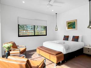 a bedroom with a bed and a couch and chairs at Sereno in Pokolbin
