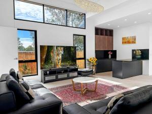 a living room with a black couch and a tv at Sereno in Pokolbin