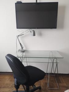 a black chair sitting in front of a desk with a television at Habitación Doble en Dpto compartido in Santiago +3 photos