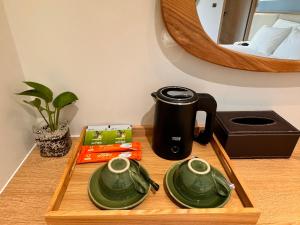 a coffee maker on a wooden tray with two green dishes at The Sol Hotel in Phú Quốc