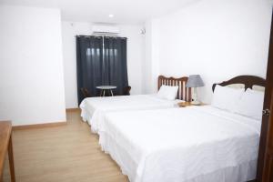 two beds in a room with white sheets at Koa Guest House in Angeles