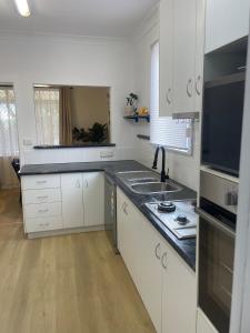 a kitchen with white cabinets and a counter top at Easy Wagga Stopover, Spacious & Comfortable in Forest Hill