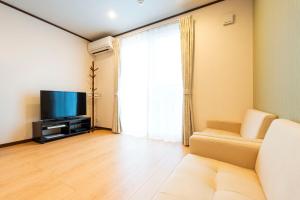 a living room with a couch and a television at アドベンまで5分で4連棟の最大30名のゲストハウス in Shirahama