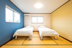 two beds in a room with blue walls and windows at アドベンまで5分で4連棟の最大30名のゲストハウス in Shirahama